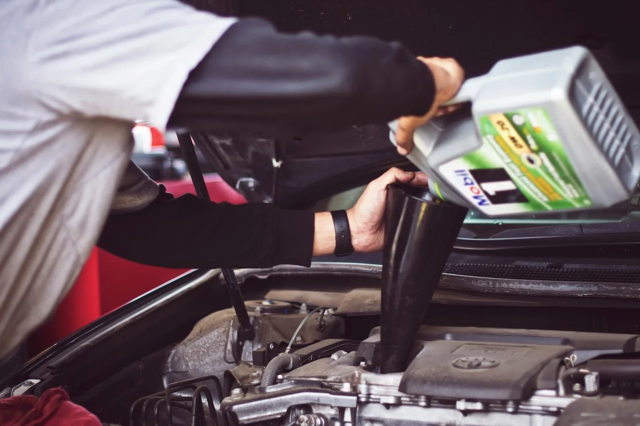 Man refilling motor oil on car engine bay photo